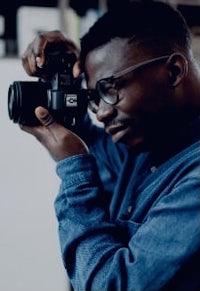 a man with glasses taking a picture with his camera